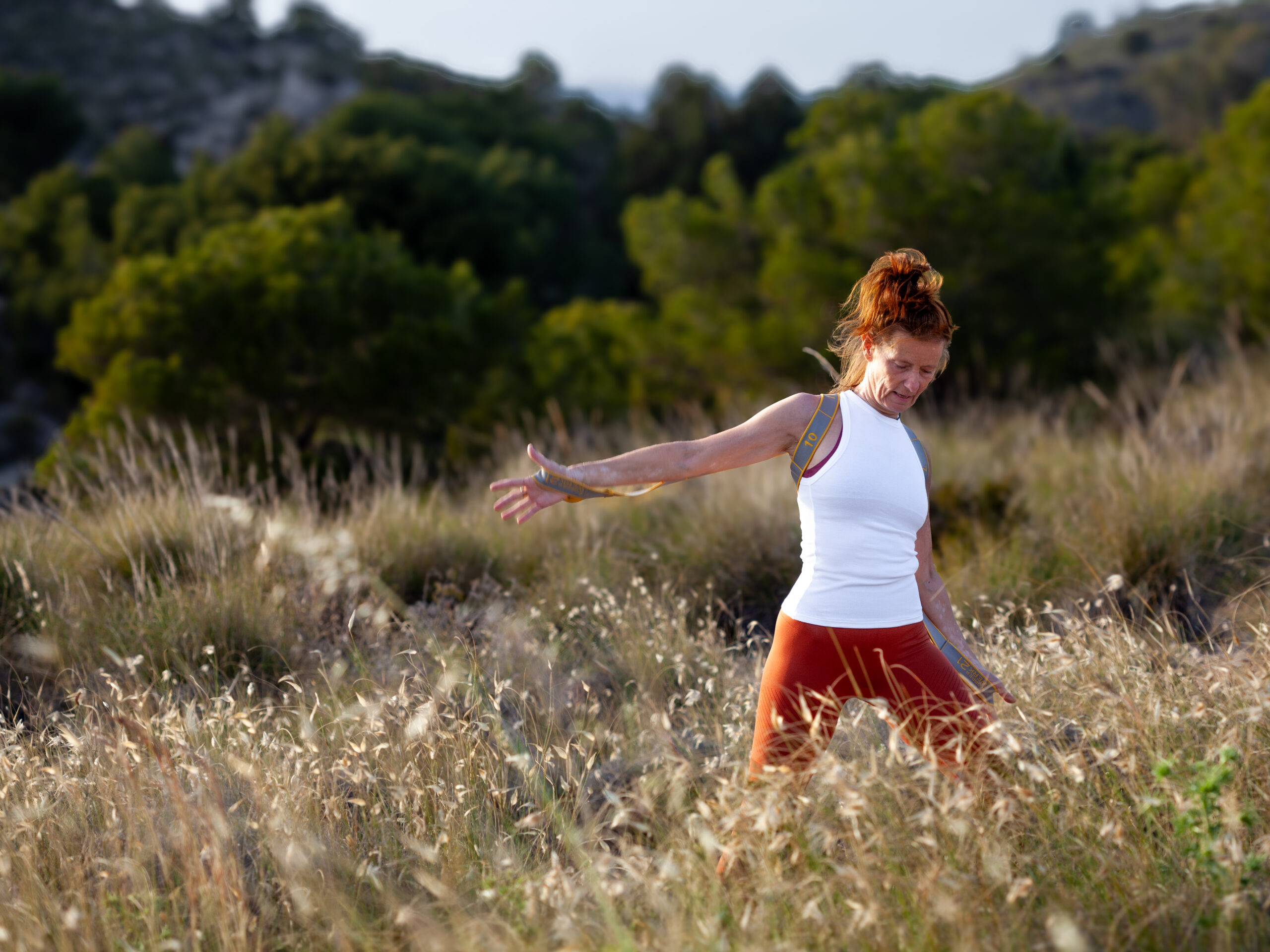 Woman doin easy exercise in high grass on a cliff