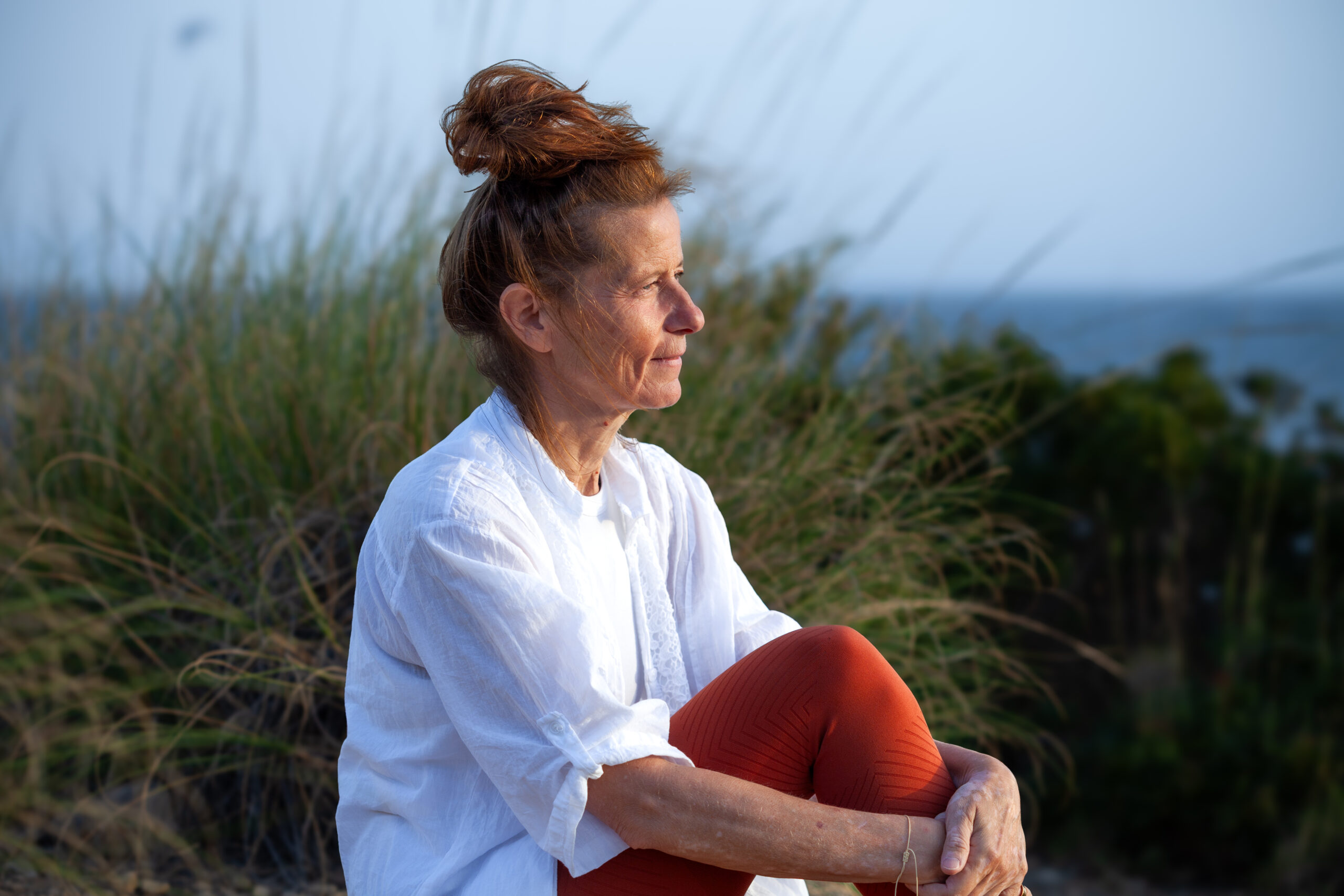 sunset woman sitting in high grass at the cliff in spain